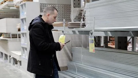 Comparing hardware store prices on smartphone, male browsing construction Stock Photos