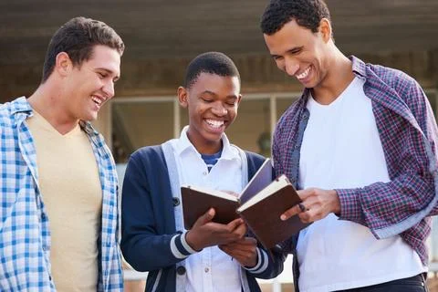 Comparing notes. Cropped shot of a group of university students looking through Stock Photos