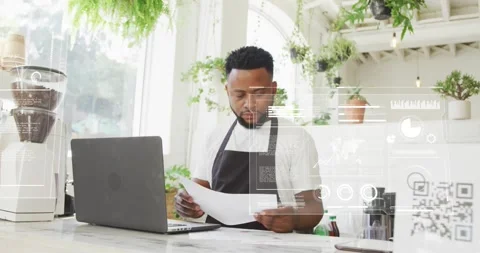 Comparing paper sheets with laptop, barista in black apron at cafe counter, data Stock Footage 333901118