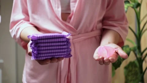 Comparison of reusable silicone menstrual cups stack purple pads. Girl in pi Stock Footage 196978992