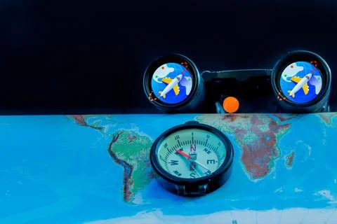 Compass and binoculars on a world map with travel icons, symbolizing global n Stock Photos