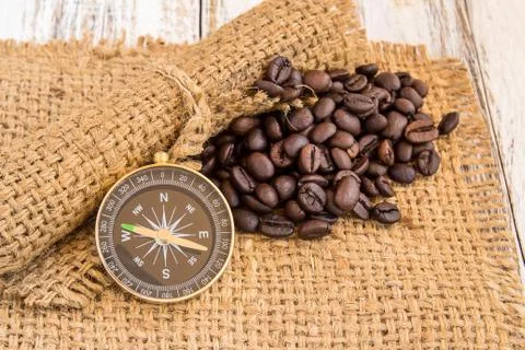 Compass and coffee beans on burlap sack on wooden background Foto stock