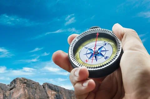 Compass and hand in mountains Stock Photos