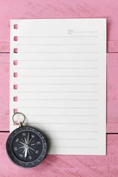 Compass and note paper on the pink wooden floor. Stock-Fotos