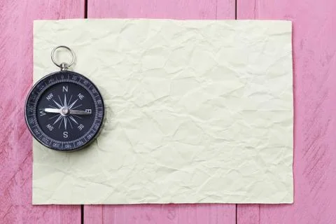 Compass and note paper on the pink wooden floor. Stock Photos