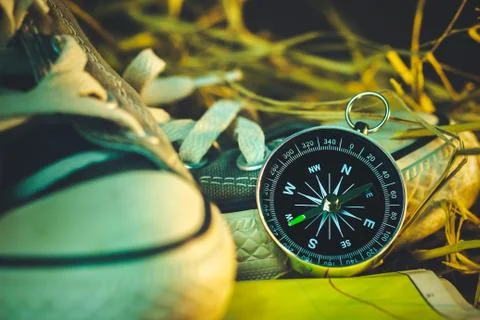 Compass and paper map with sneaker and pine cone placed on dry wheat straw. Stock Photos