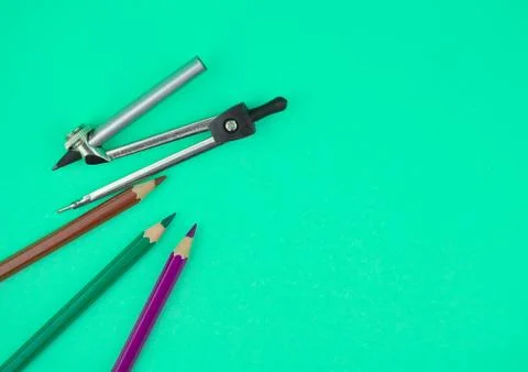 A compass and three different color wood pencil crayons placed on top of a li Stock Photos