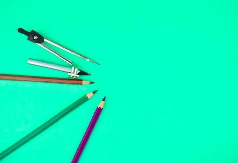 Compass and three different color wood pencil crayons placed on top of a ligh Stock Photos