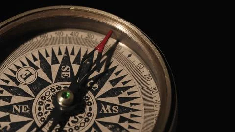 Compass with an arrow with a red tip close up on a black background. Equipment Stock Photos