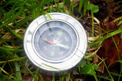 Compass on background of summer grass as symbol of tourism Stock Photos