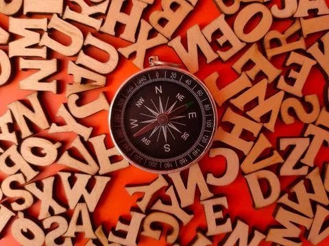 Compass centered among a random assortment of small, wooden alphabet letter.. Stock Photos