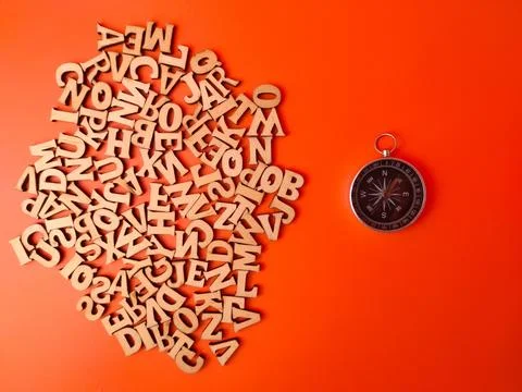 Compass centered among a random assortment of small, wooden alphabet letter.. Stock Photos