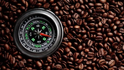 Compass on dark roasted coffee beans. Coffee beans and compass, top view. Stock Footage 257871528