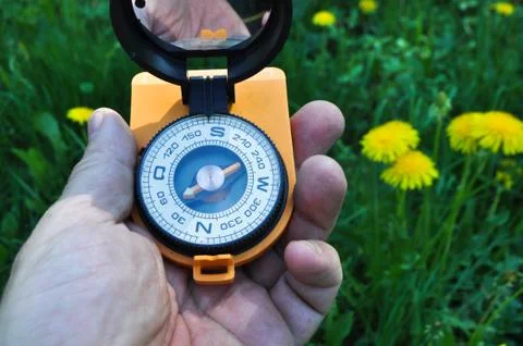 Compass in hand, against the background of blooming meadows. Stock Photos