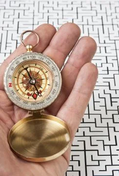 Compass in hand on the background of the labyrinth Stock Photos
