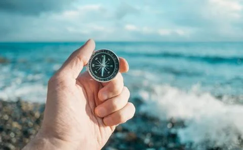 Compass in hand in the background the waves and the sea. Stock Photos