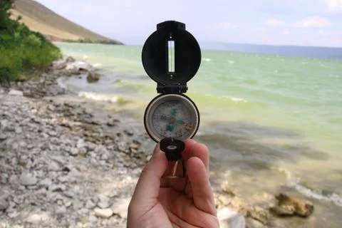 Compass in the hand on the nature background. Stock Photos