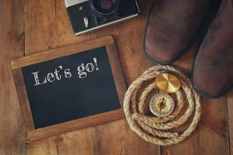 Compass, hiking boots, old camera and blackboard with quote Stock Photos