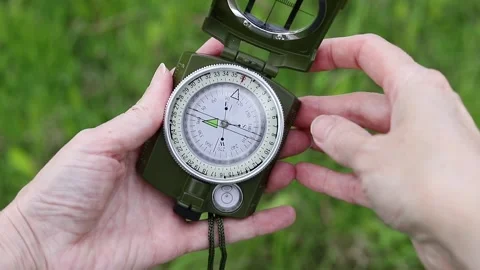 Compass in human hands against a background of green grass Stock Footage 336279582