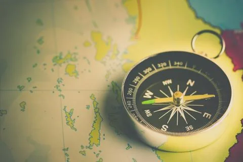 Compass laid on a paper map. Stock Photos
