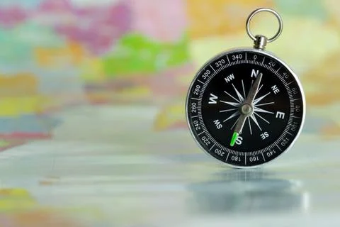 Compass laid on a paper map. Stock Photos