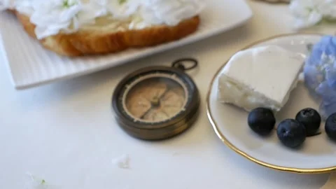 The compass lies on the table next to a plate of cheese and berries. Stock Footage 334941644
