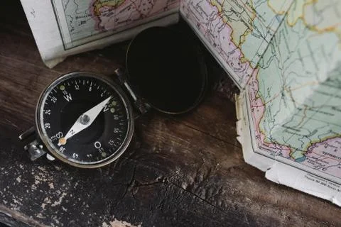Compass lying on a wooden table next to the map Stock Photos