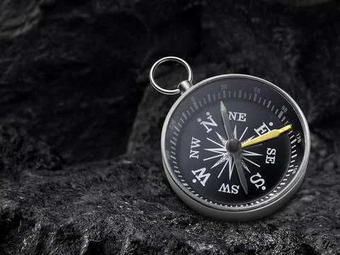 Compass nestled on black coal background. Travel destination and navigation.. Stock Photos