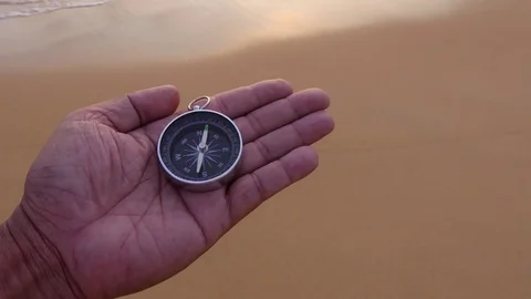 A compass in the palm of my hand that is looking for a destination on the beach 库存影片 77569720