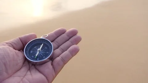 A compass in the palm of my hand that is looking for a destination on the beach 库存影片 77570134
