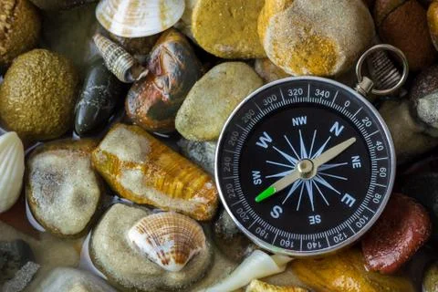 Compass on the pebbles and shell at riverside. Stock Photos