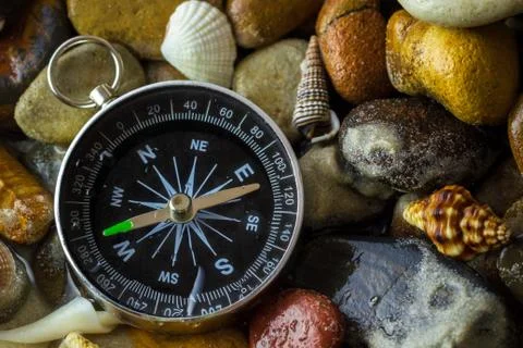 Compass on the pebbles and shell at riverside. Stock Photos