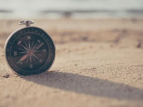 Compass is placed on the beach and sunshine in the evening sunset Stock Photos