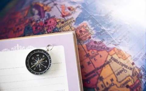 A compass placed on a notebook on the map background travel geographic naviga Stock Photos