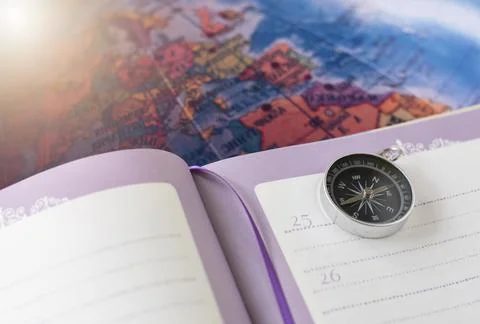 A compass placed on a notebook on the map background travel geographic naviga Stock Photos