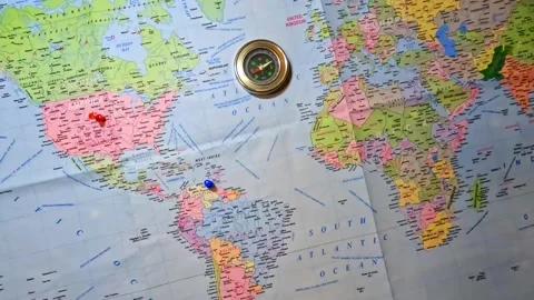 Compass on Printed World Map marked USA and Venezuela with thumb pins. Stock Footage 341164543