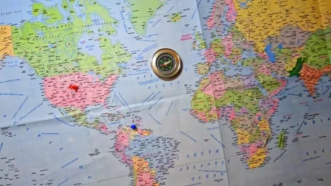 Compass on Printed World Map marked USA and Venezuela with thumb pins. Stock Footage 341164585
