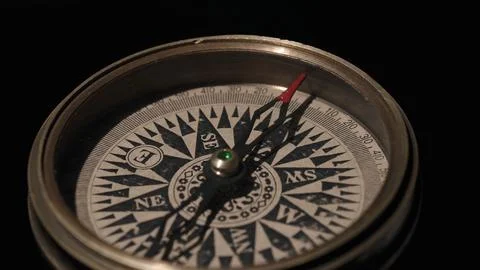 Compass with a red arrow indicating the direction on a black background. Concept Stock Photos