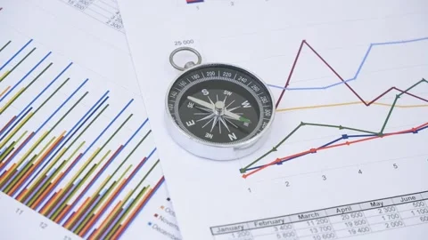 Compass with rotating pointer on financial charts and graphs. Stock Footage 269896032