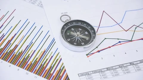 Compass with rotating pointer on financial charts and graphs. Stock Footage 269896392