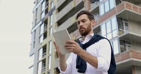 Competent bearded architect using digital tablet for estimating construction of Stock Footage 140681372