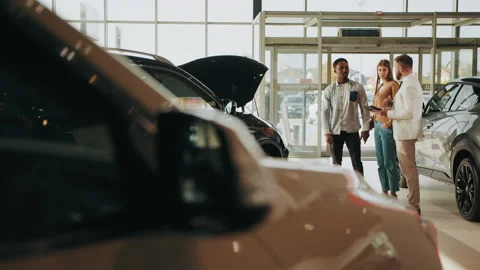 Competent car dealer using digital tablet for work with clients at showroom Stock Footage 175848054