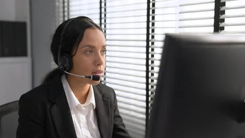 Competent female operator working on computer and while talking with clients. Foto stock