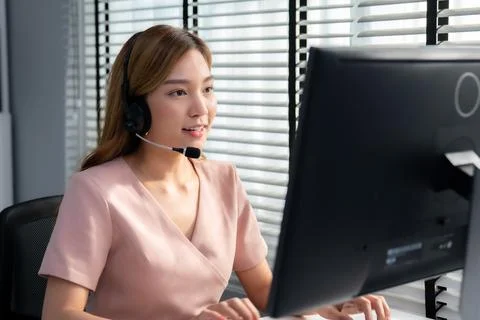 Competent female operator working on computer and while talking with clients. Foto stock