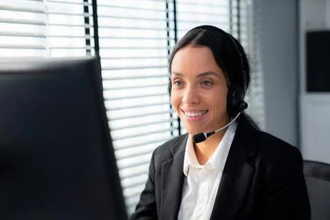 Competent female operator working on computer and while talking with clients. Foto stock