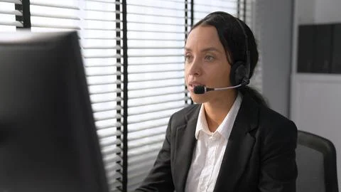 Competent female operator working on computer and while talking with clients. Foto stock