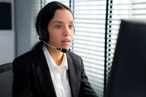 Competent female operator working on computer and while talking with clients. Foto stock