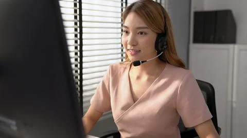 Competent female operator working on computer and while talking with clients. Foto stock