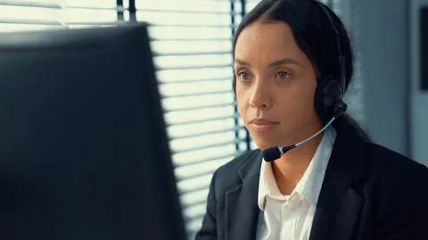 Competent female operator working on computer and while talking with clients. Foto stock