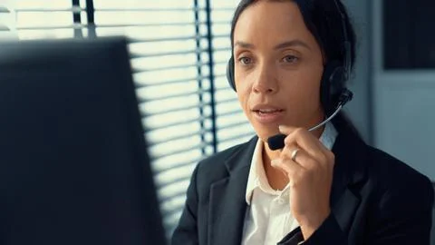 Competent female operator working on computer and while talking with clients. Foto stock